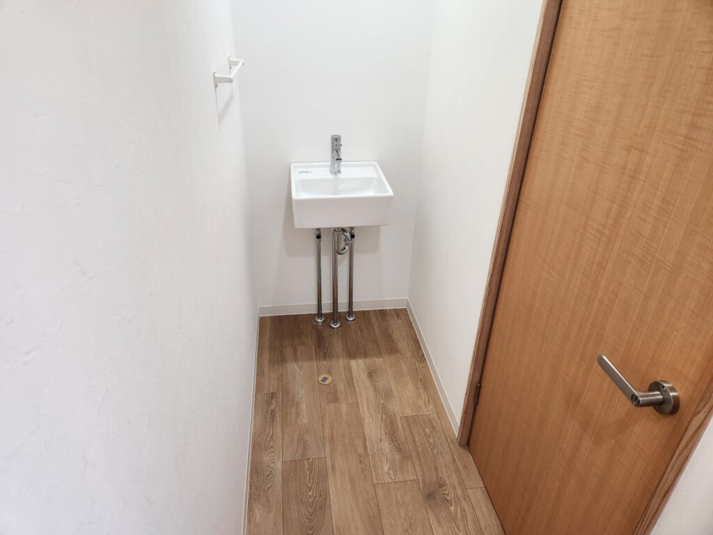 施工後：木目調の床と手洗い器を備えたスペース。